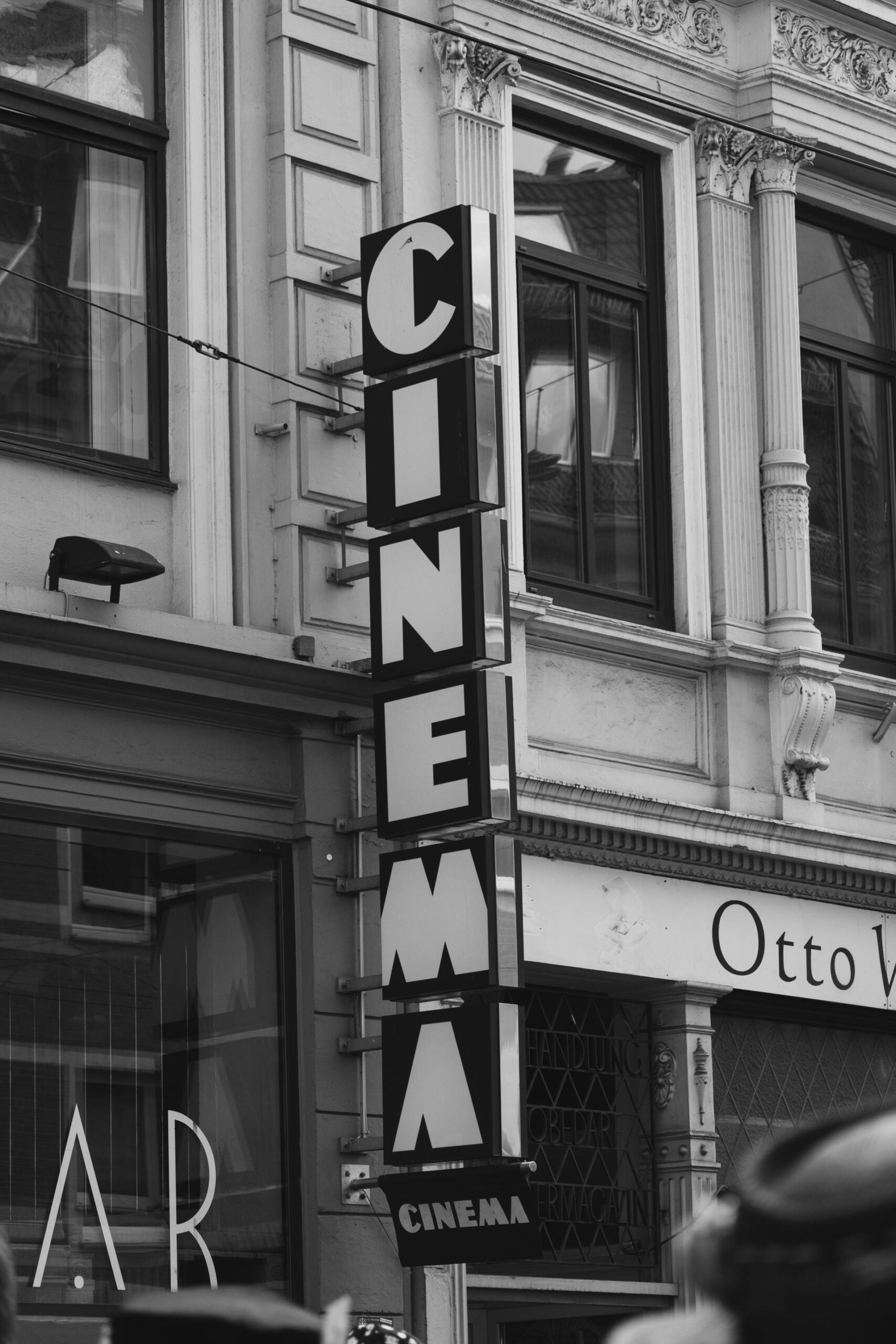 Startseite A vertical black and white photo of a city cinema sign on a building's facade.