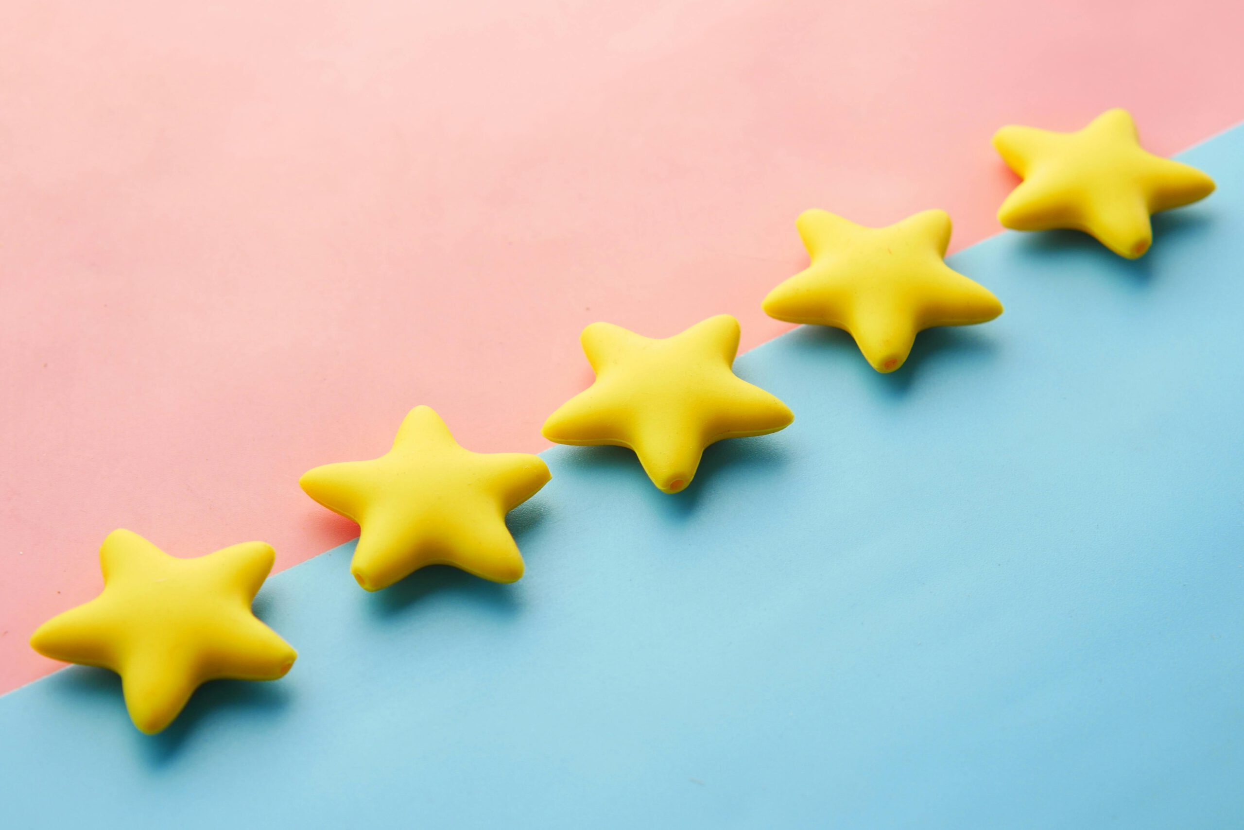 Startseite Yellow stars on pink and blue pastel background for rating or review concept.